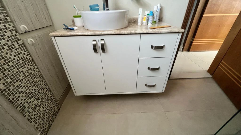 Banheiro planejado simples com gabinete branco, três gavetas, portas centrais e cuba de apoio redonda – Art Closet